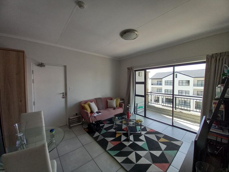 Open plan living area featuring tiled flooring, a built-in cupboard, and large sliding glass doors providing access to a private balcony.