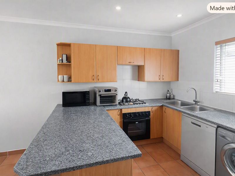 Functional kitchen featuring laminate cabinetry, granite-look countertops, built-in oven, gas hob, and tiled flooring with a breakfast bar extension.