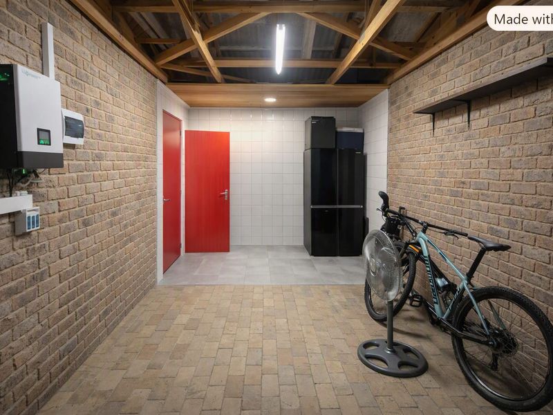 A clean, well-maintained garage featuring exposed timber roof trusses, brick walls, and durable tiled flooring, equipped with an integrated inverter system.