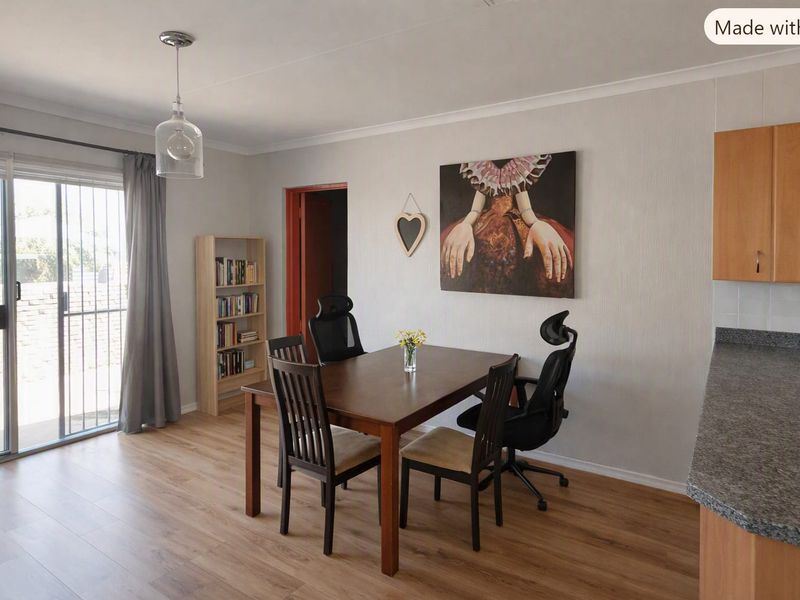 Open plan living and dining area featuring laminate flooring, modern pendant lighting, and direct access to an outdoor patio through sliding glass doors.