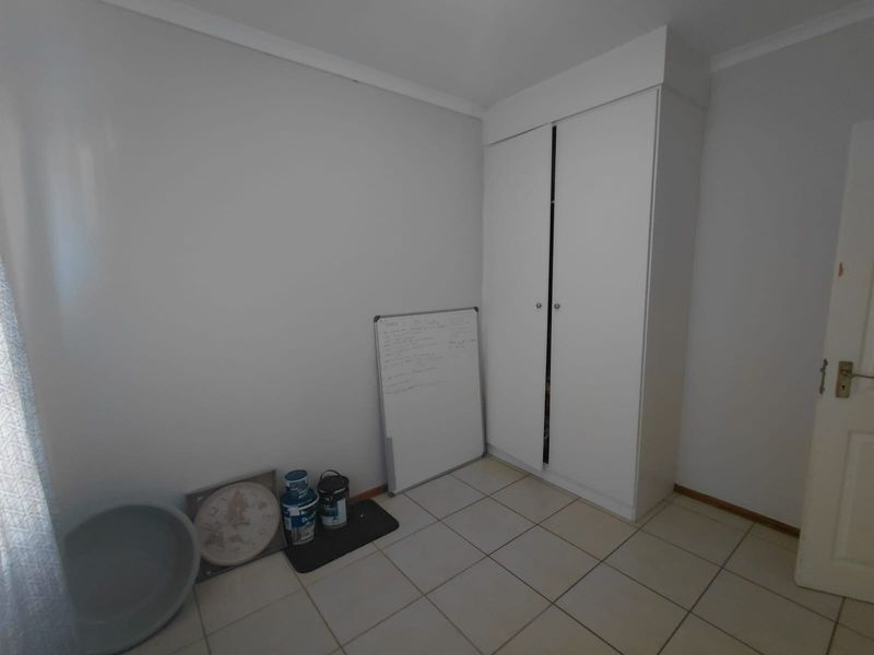 A clean, empty bedroom featuring neutral tiled flooring and a built-in white wardrobe, offering a versatile space ready for personalization.