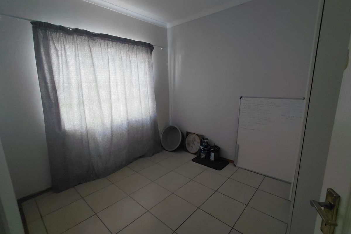 A vacant bedroom featuring neutral wall paint, tiled flooring, and a curtain rod, offering a blank canvas for personalization.