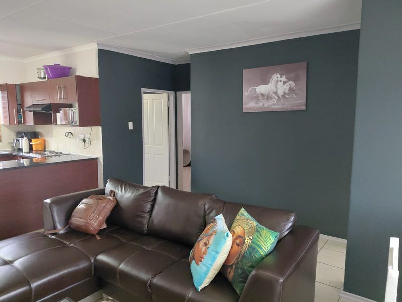 Open-plan living area featuring a kitchen with built-in cabinetry, granite countertops, and tiled flooring, seamlessly connected to the lounge space.