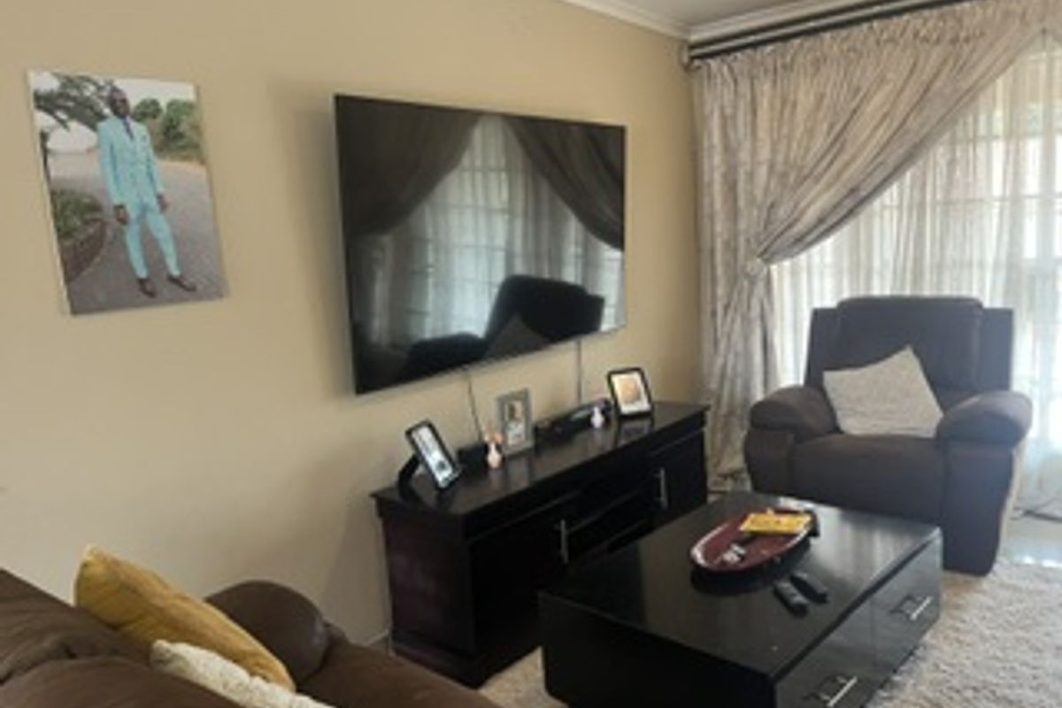 A comfortable living room featuring a wall-mounted television and large sliding glass doors that provide access to natural light.
