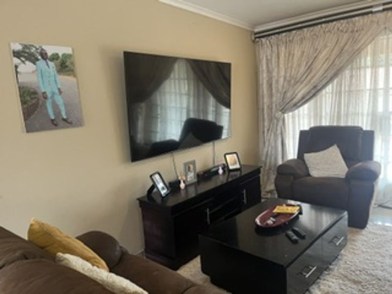 A comfortable living room featuring a wall-mounted television and large sliding glass doors that provide access to natural light.
