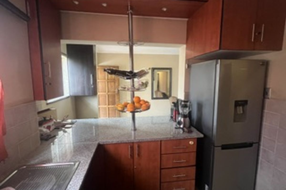 A functional kitchen featuring granite countertops, ample built-in cabinetry, and a tiled backsplash, providing a practical workspace for daily meal preparation.