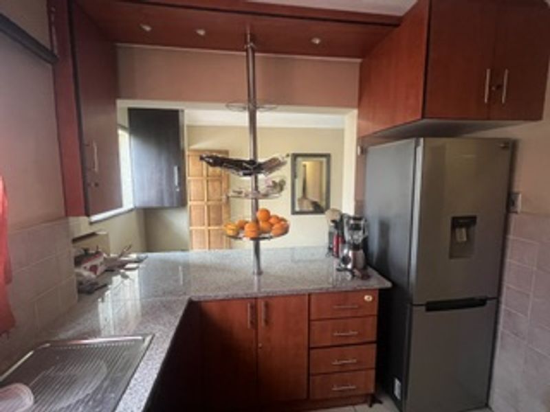 A functional kitchen featuring granite countertops, ample built-in cabinetry, and a tiled backsplash, providing a practical workspace for daily meal preparation.