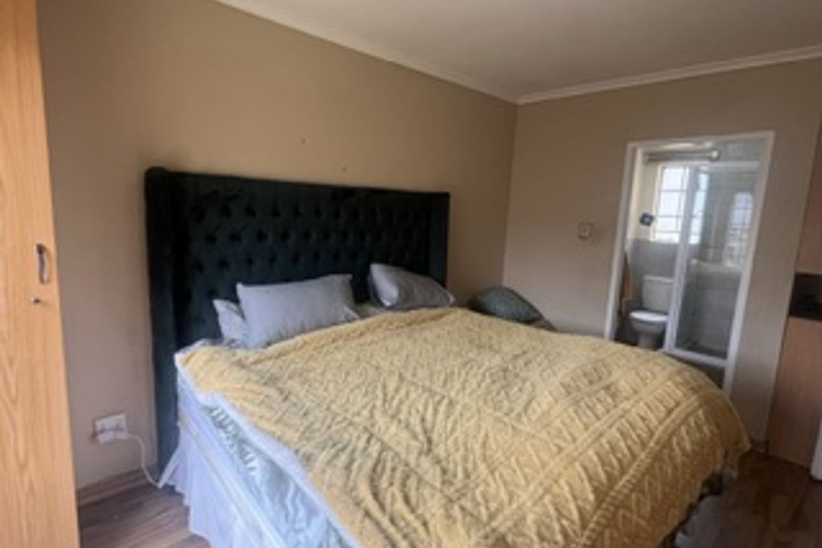 A bedroom featuring laminate flooring, a built-in wardrobe, and direct access to an en-suite bathroom.