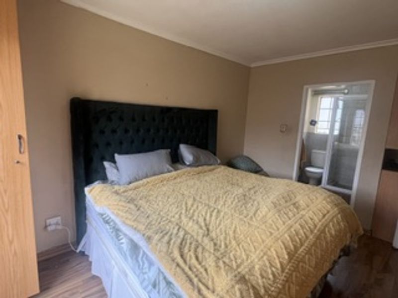 A bedroom featuring laminate flooring, a built-in wardrobe, and direct access to an en-suite bathroom.