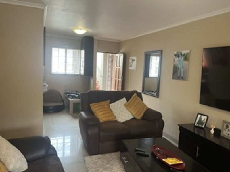 A living room area featuring tiled flooring and neutral wall finishes, providing a functional space with access to an adjacent room.