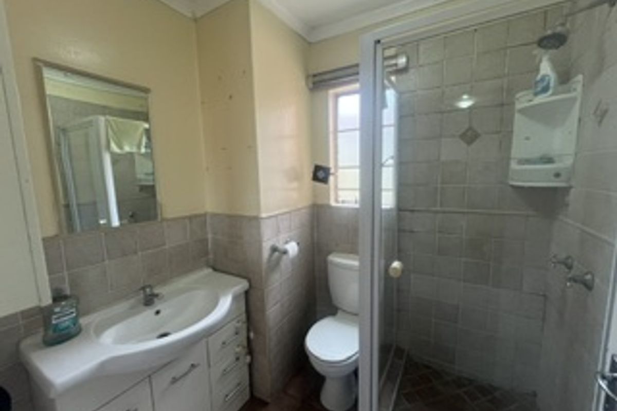 A functional bathroom featuring a vanity cabinet with basin, a separate shower enclosure, and a toilet, with tiled finishes throughout.