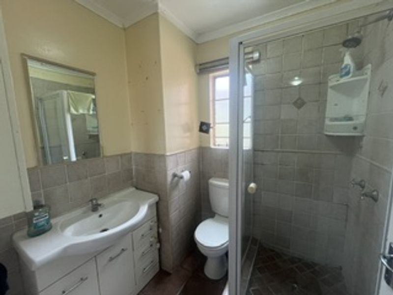 A functional bathroom featuring a vanity cabinet with basin, a separate shower enclosure, and a toilet, with tiled finishes throughout.