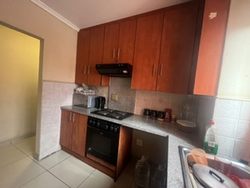 A functional kitchen featuring wooden cabinetry, granite countertops, a built-in oven, gas hob, and tiled backsplash, offering a practical layout for daily cooking.