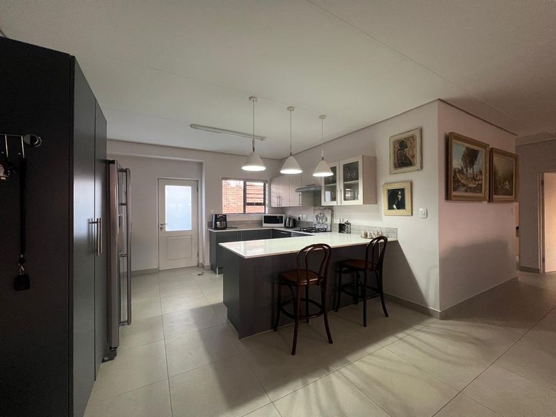 Modern kitchen featuring a central island with breakfast bar seating, stone countertops, ample built-in cabinetry, and sleek tiled flooring.