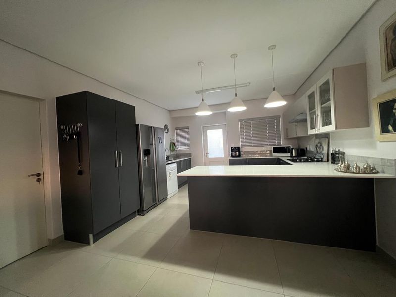 Modern kitchen featuring a central island with quartz countertops, ample built-in cabinetry, pendant lighting, and tiled flooring.