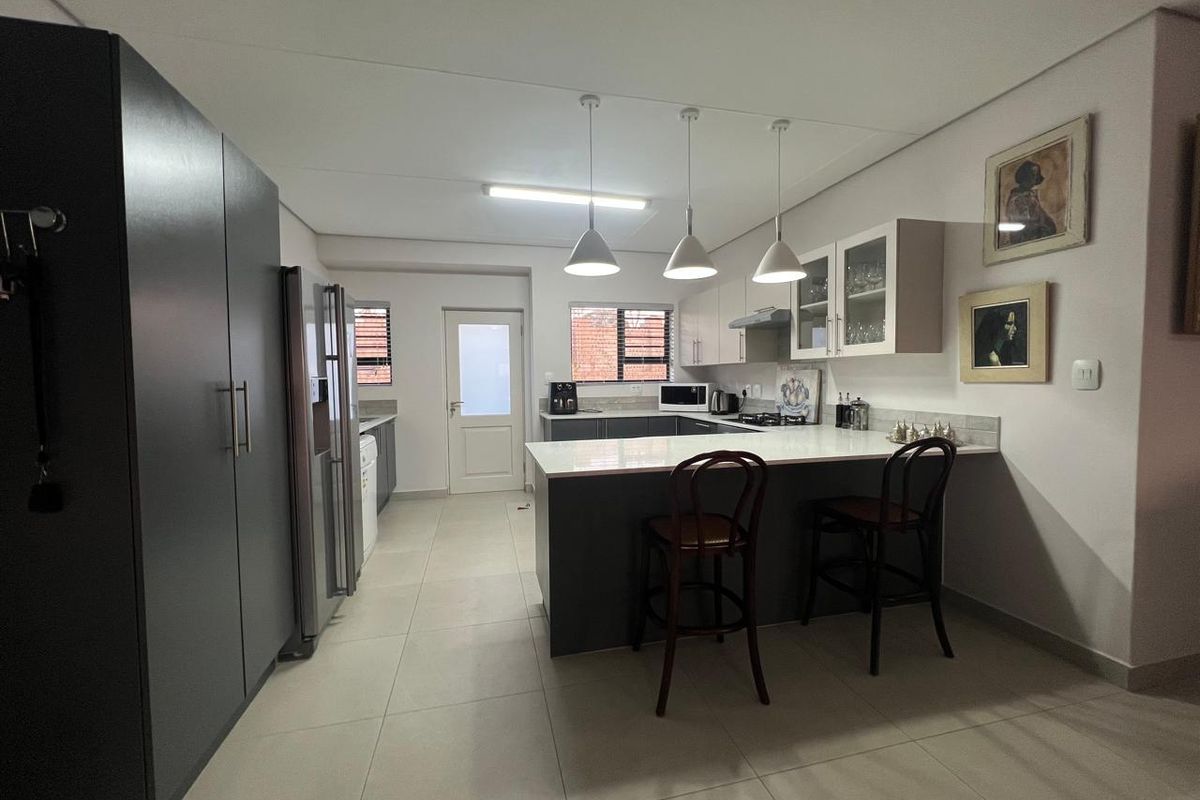 Modern kitchen featuring a central island with breakfast bar seating, sleek cabinetry, quartz countertops, and contemporary pendant lighting.