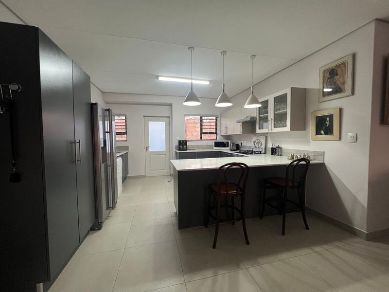 Modern kitchen featuring a central island with breakfast bar seating, sleek cabinetry, quartz countertops, and contemporary pendant lighting.