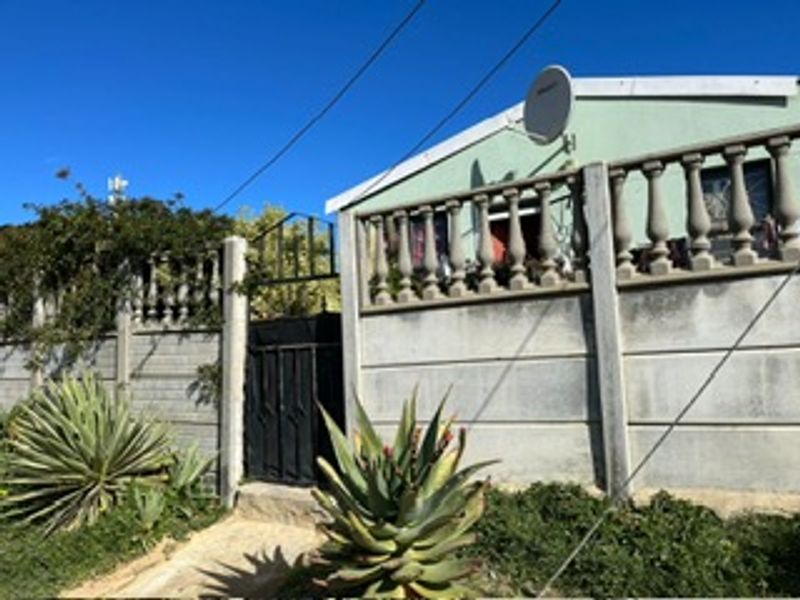 Front exterior view of the property featuring a precast concrete boundary wall, decorative concrete balustrade, and a secure metal pedestrian gate.