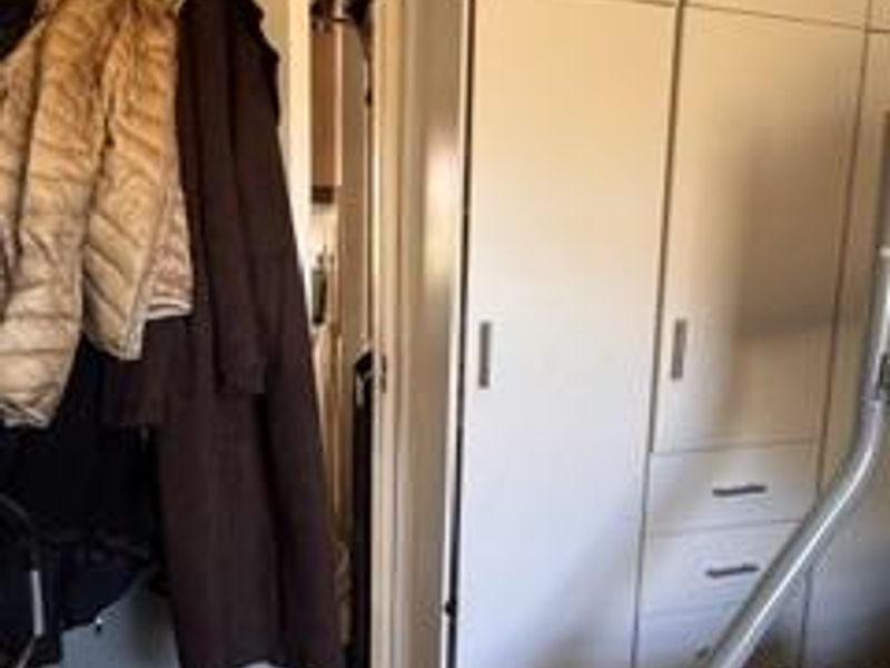 A bedroom featuring floor-to-ceiling built-in wardrobes with integrated drawers and classic coving detail.