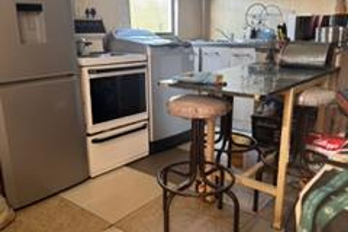 A compact kitchen featuring built-in cabinetry, a sink, and tiled flooring, offering a functional layout with potential for modernization.