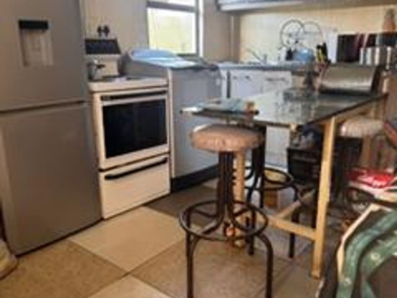 A compact kitchen featuring built-in cabinetry, a sink, and tiled flooring, offering a functional layout with potential for modernization.
