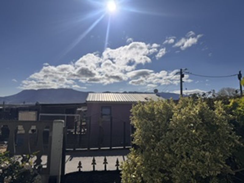 Front exterior view of the property featuring a metal roof, boundary fencing, and gate with mountain views in the background.
