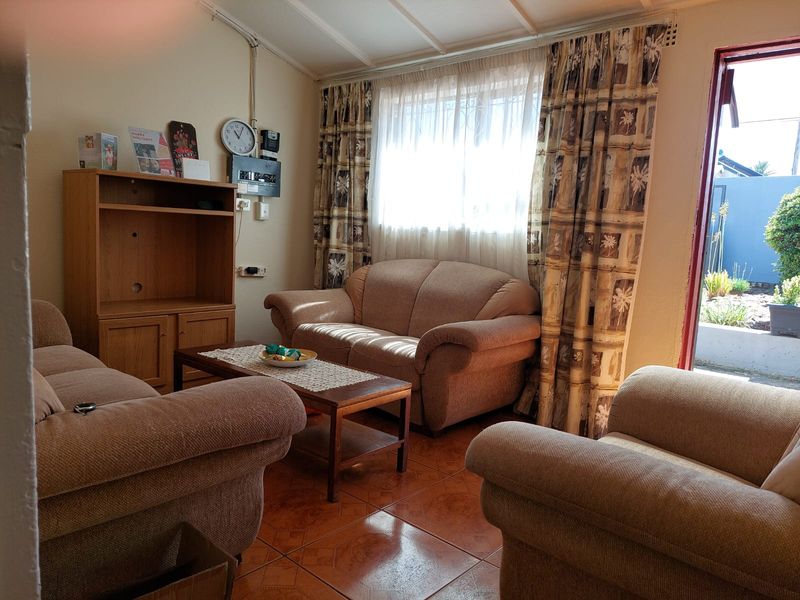 A living room featuring tiled flooring and exposed beam ceilings, with direct access to an outdoor patio area.