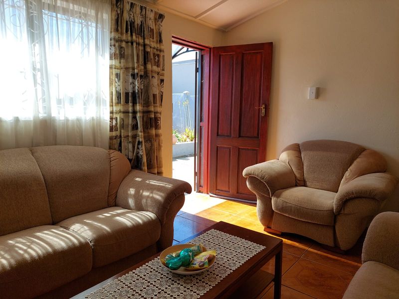 A living room featuring tiled flooring and direct access to an outdoor area through a timber door.