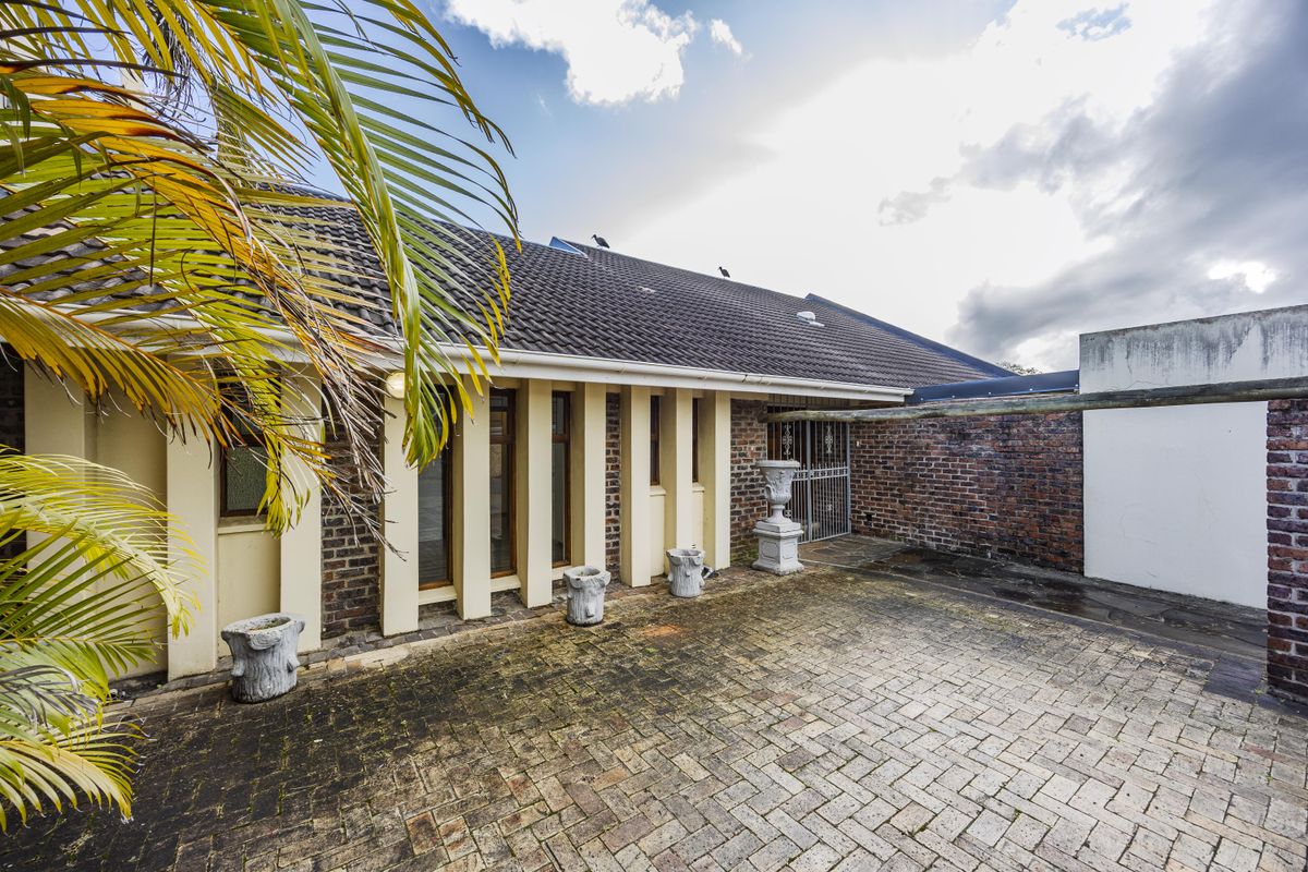 A rear courtyard area featuring paved flooring, brick wall construction, and a tiled roof structure with security gate access.