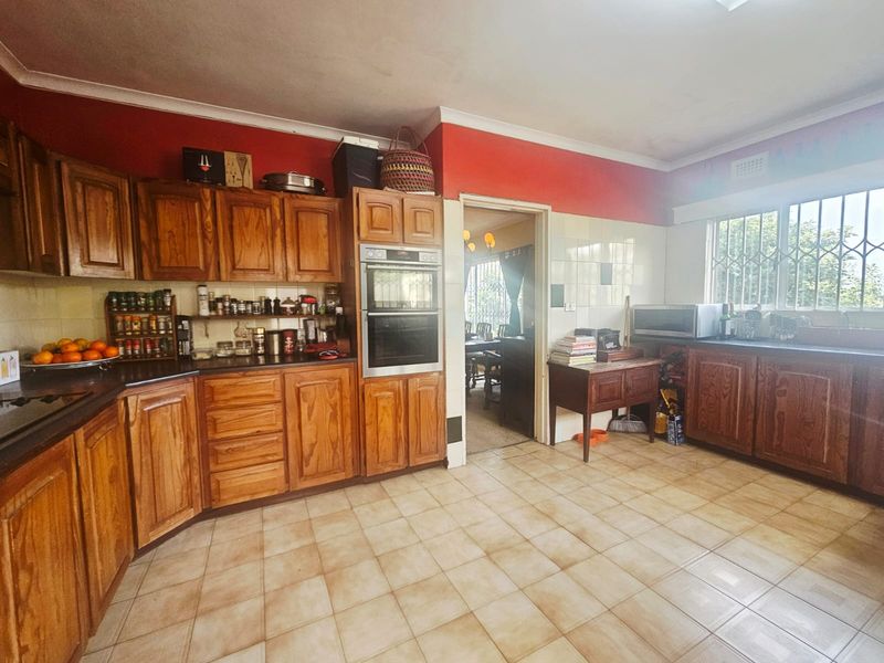 A functional kitchen featuring traditional wooden cabinetry, a built-in double oven, tiled flooring, and a tiled backsplash with direct access to the dining area.