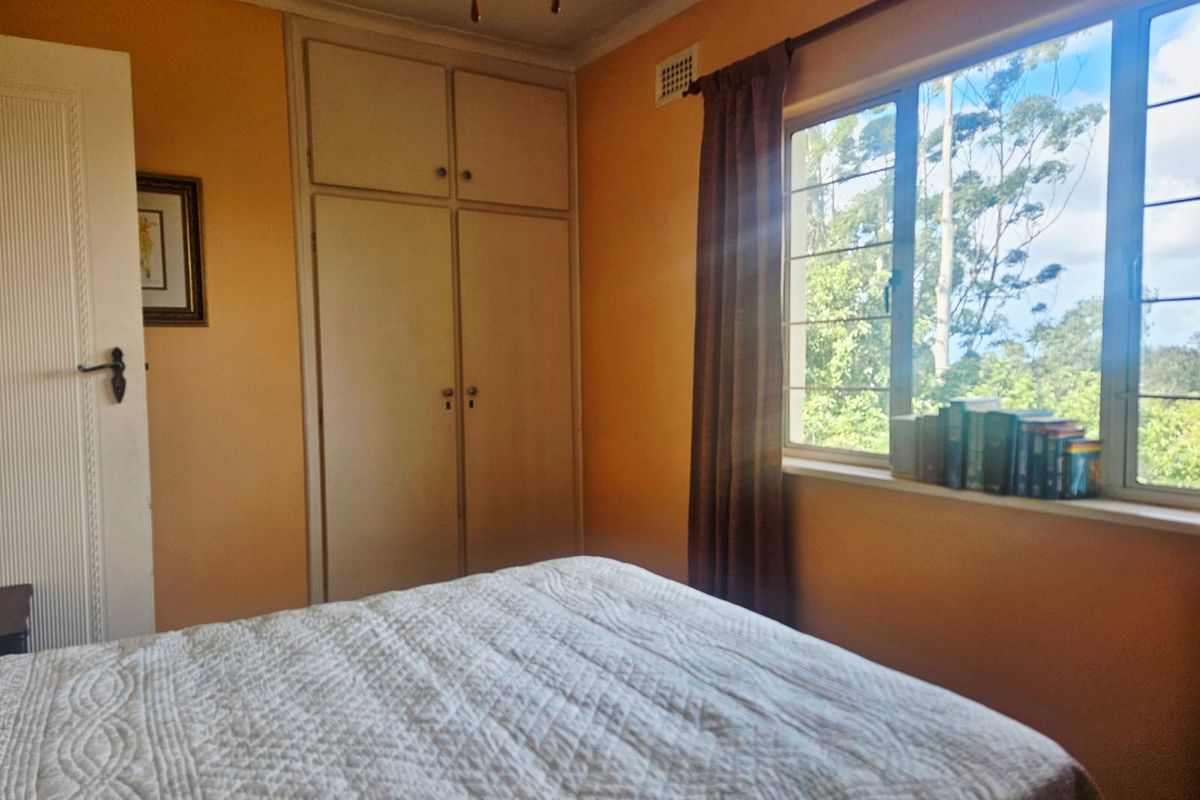 A bedroom featuring built-in cupboards, a large window with natural light, and neutral wall finishes.