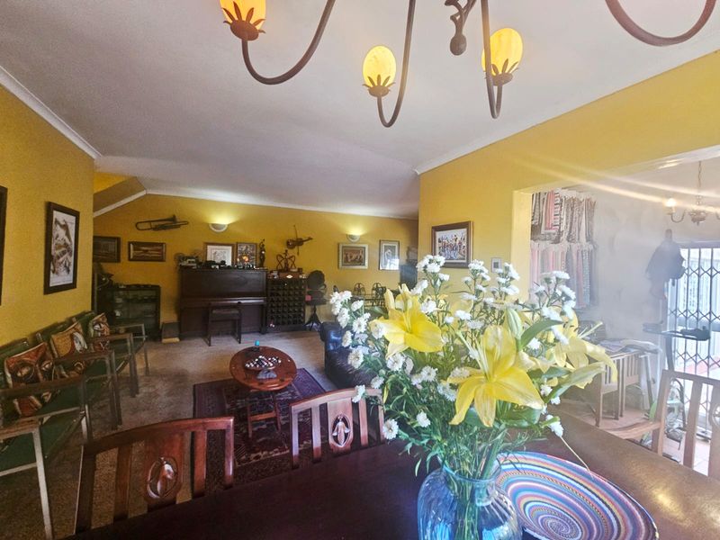 Spacious open-plan living and dining area featuring warm yellow walls, decorative wall sconces, and a central chandelier.