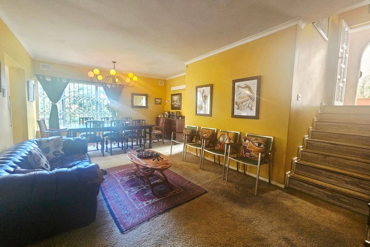 Spacious living area featuring a staircase, coving, and security gate, offering a functional layout with potential for modern updates.