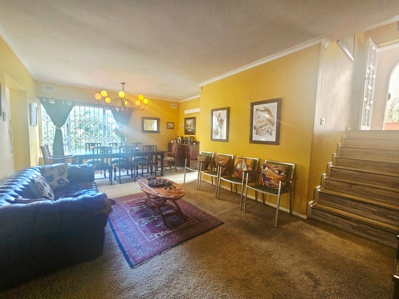 Spacious living area featuring a staircase, coving, and security gate, offering a functional layout with potential for modern updates.