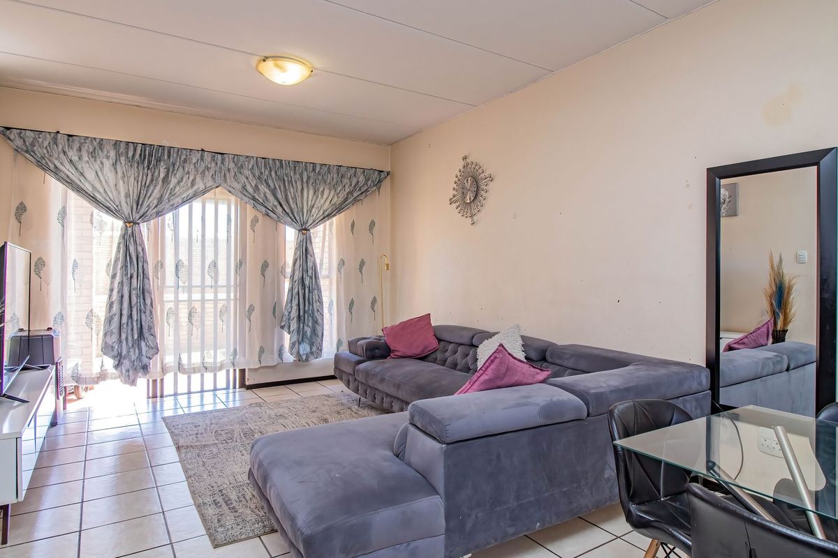 A living room featuring tiled flooring and a sliding glass door providing access to an outdoor area, with neutral wall finishes.