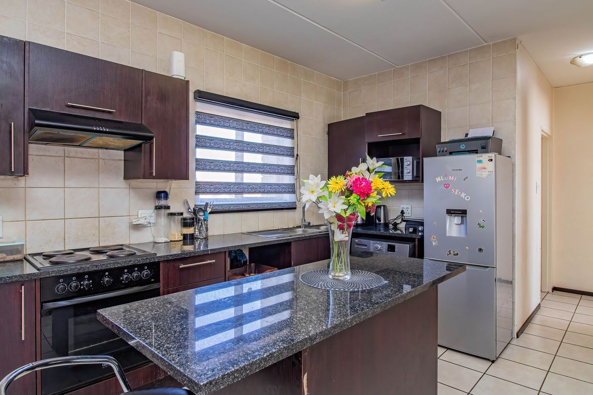 A functional kitchen featuring dark wood cabinetry, granite countertops, a built-in oven with hob, and a tiled backsplash.