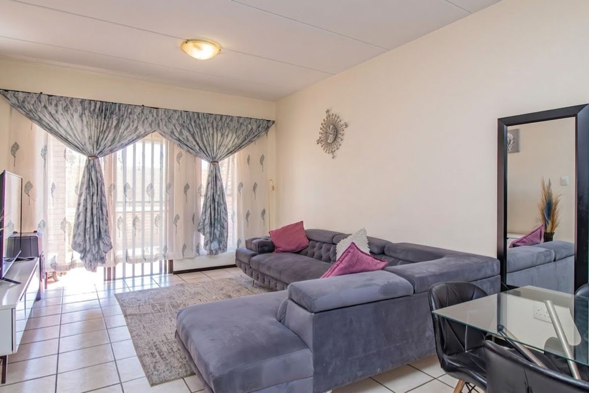A bright living room featuring tiled flooring and a large sliding glass door providing access to the outdoor area.