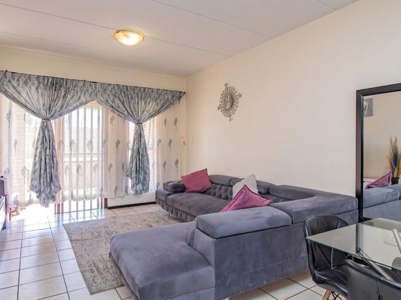 A bright living room featuring tiled flooring and a large sliding glass door providing access to the outdoor area.