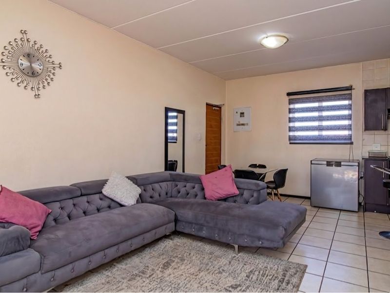 Open-plan living area featuring tiled flooring and a compact kitchen with built-in cabinetry and an extractor fan.