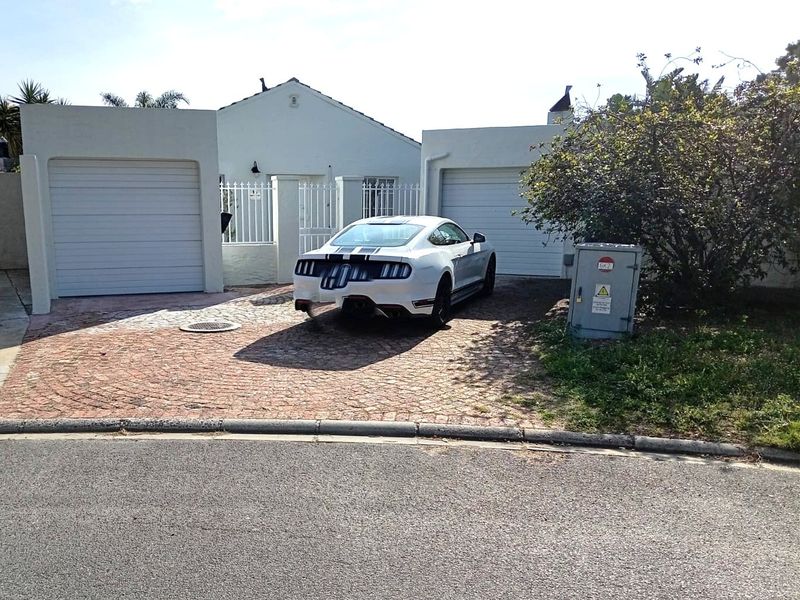 Front view of the property featuring a paved driveway, double garage doors, and secure boundary wall with gated entrance.