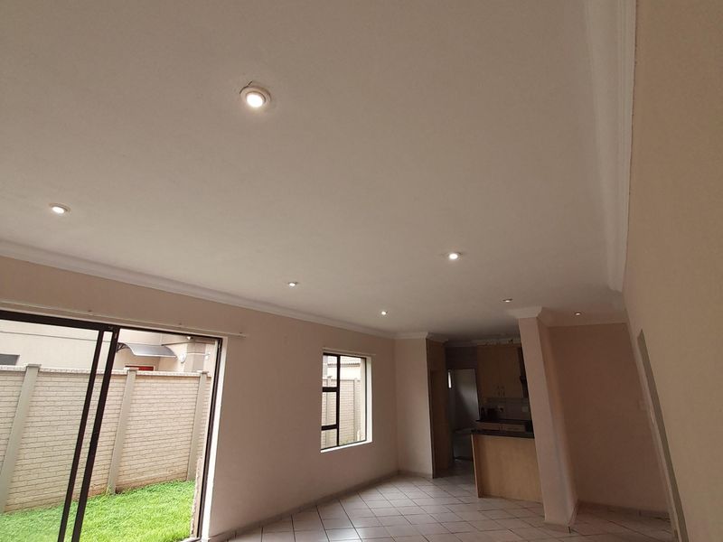 Spacious open-plan living area featuring tiled floors, recessed lighting, and direct access to the rear garden through sliding glass doors.