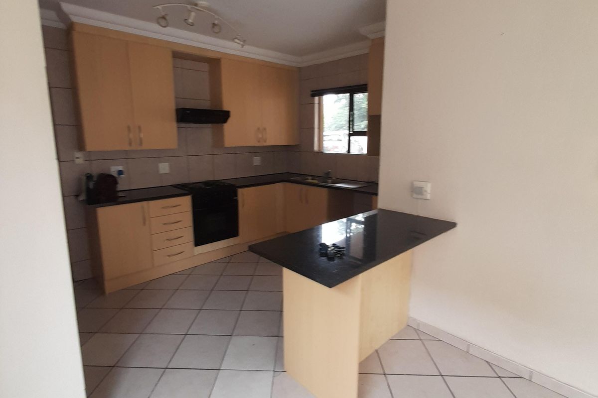 A functional kitchen featuring light wood cabinetry, granite countertops, a built-in oven with extractor fan, and tiled flooring with an integrated breakfast nook.