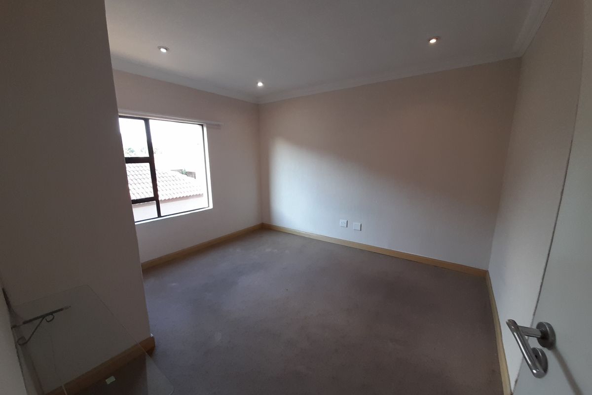 An empty bedroom featuring neutral walls, recessed downlighting, and carpet flooring, offering a blank canvas for personalization.