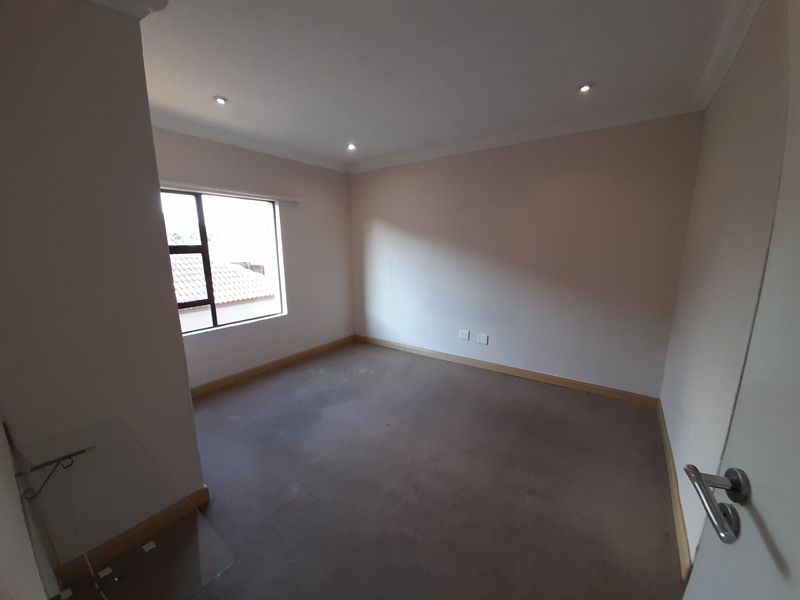 An empty bedroom featuring neutral walls, recessed downlighting, and carpet flooring, offering a blank canvas for personalization.