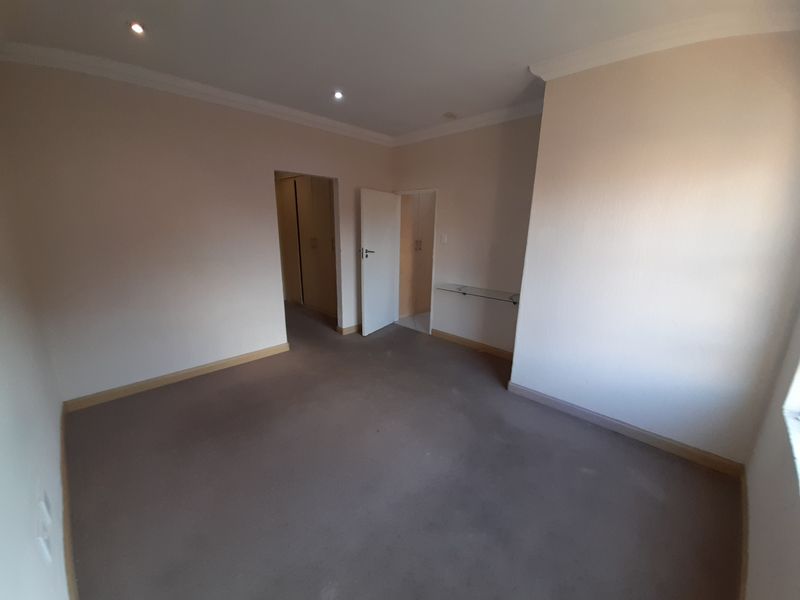 An empty bedroom featuring neutral walls, carpeted flooring, recessed downlighting, and built-in cupboard storage.