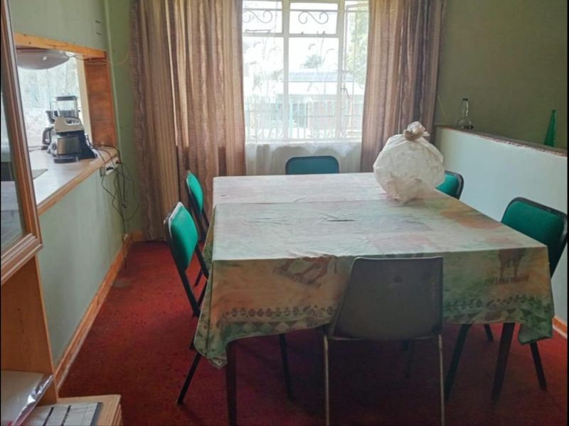 Dining room featuring a serving hatch to the kitchen, large window with natural light, and carpeted flooring.