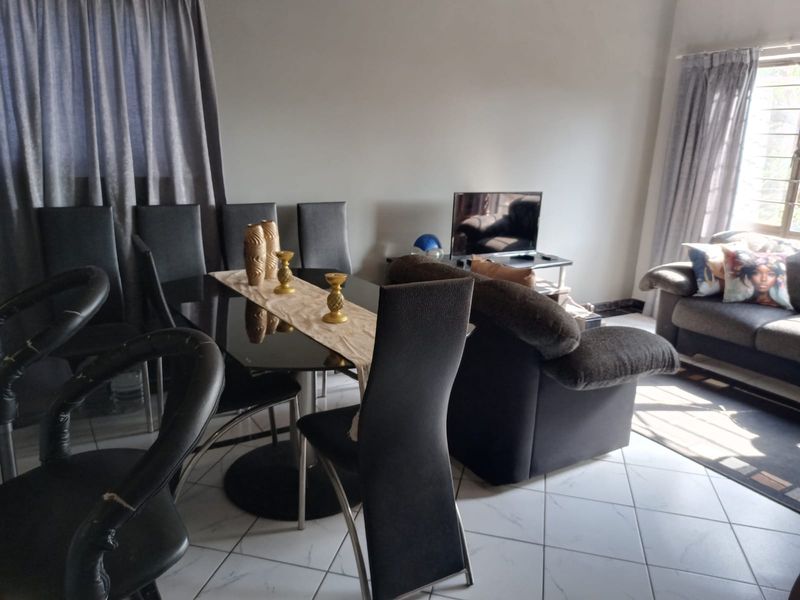 Open plan living and dining area featuring tiled flooring and natural light from large windows.