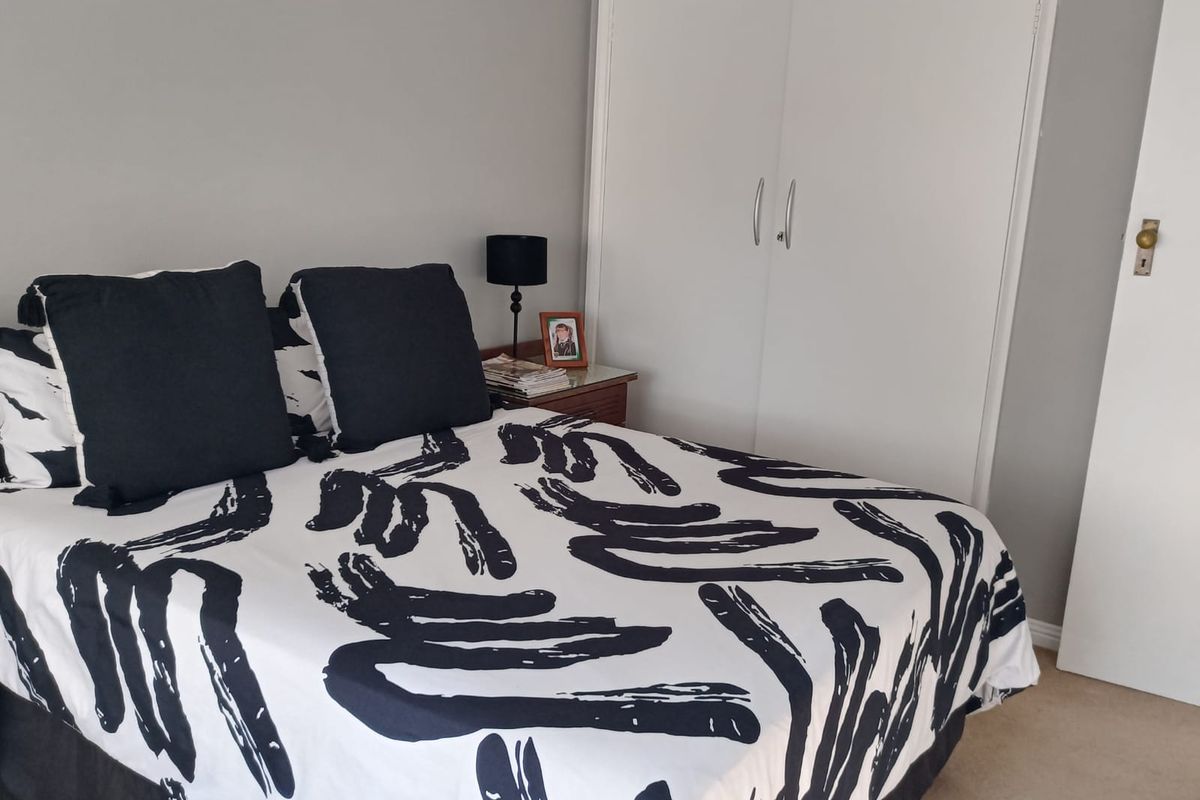 A bedroom featuring neutral wall tones and a functional built-in wardrobe with white doors.