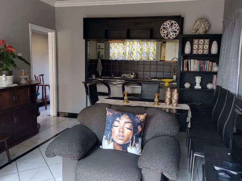 Open plan living and kitchen area featuring tiled flooring, built-in kitchen cabinetry, and a dedicated shelving unit.