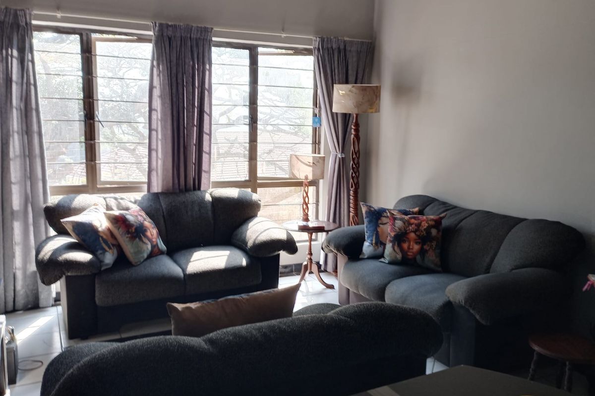 A comfortable living room featuring large windows that provide ample natural light and tiled flooring throughout.